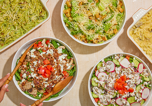 Rachel's Kitchen in Frisco, TX assorted catering salads including spinach salad with goat cheese and toasted pecans, Caesar salad, pesto pasta, and mac & cheese