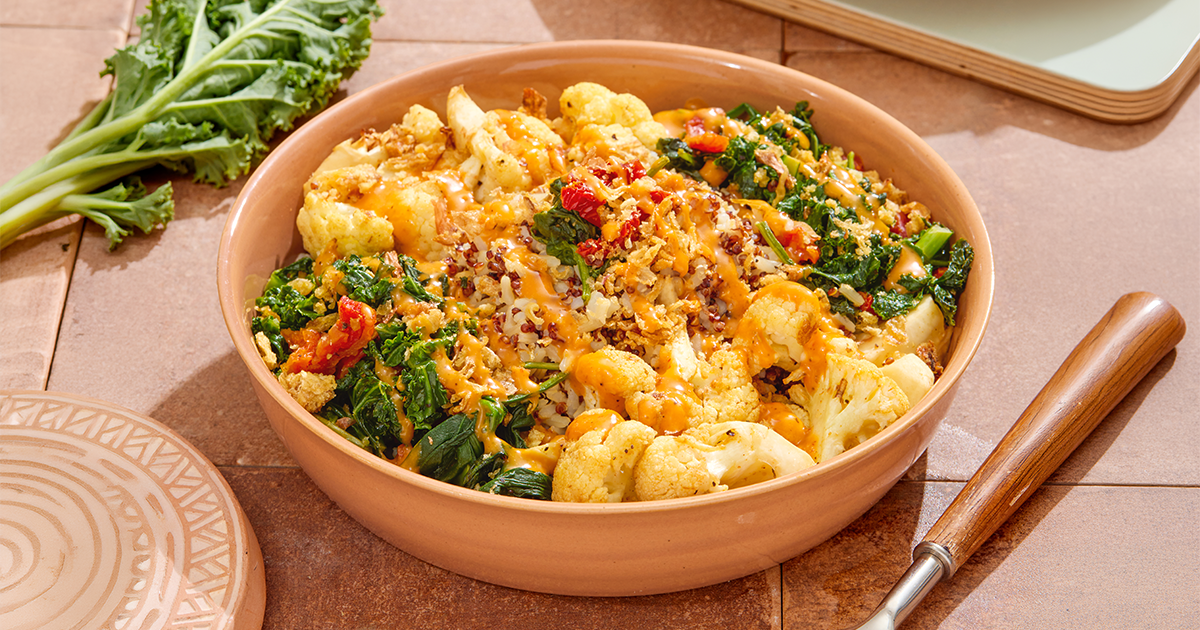 Close-up of Rachel's Kitchen Cauliflower Chipotle Grain Bowl with roasted cauliflower, crispy shallots, kale, sundried tomatoes, spinach, brown rice, quinoa, and chipotle dressing